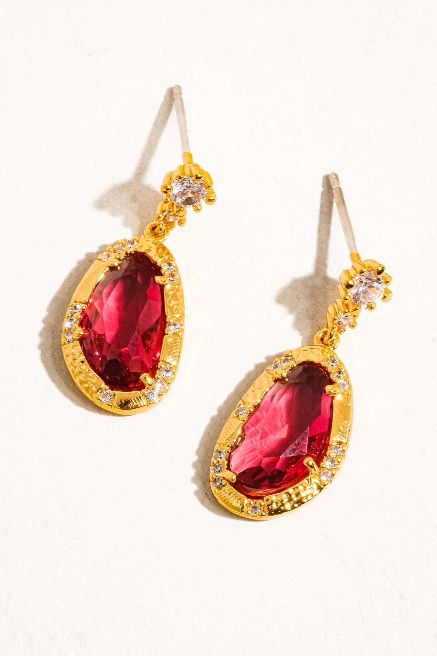 Gold earrings with red gemstones on a white background
