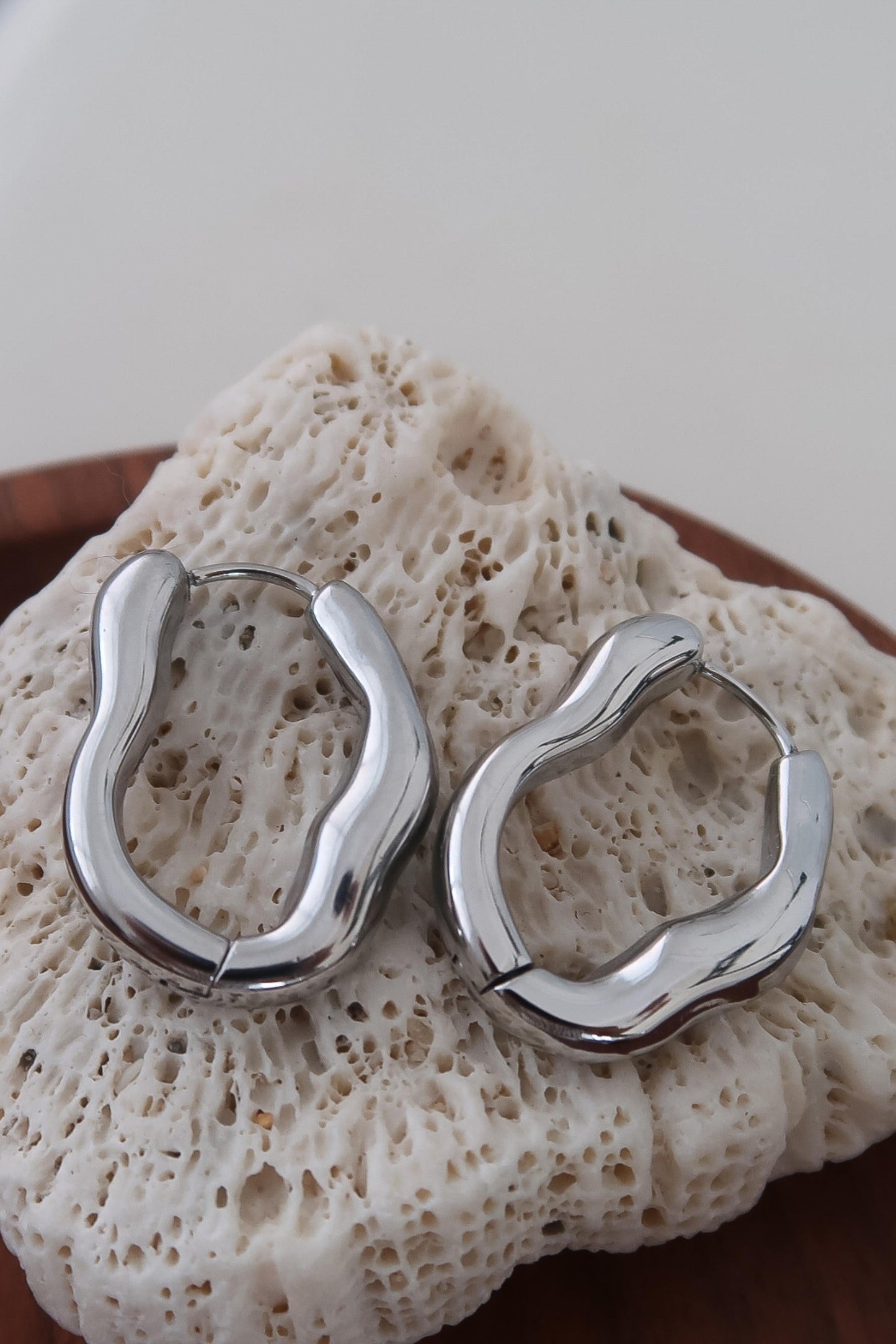 Silver hoop earrings on a textured stone surface