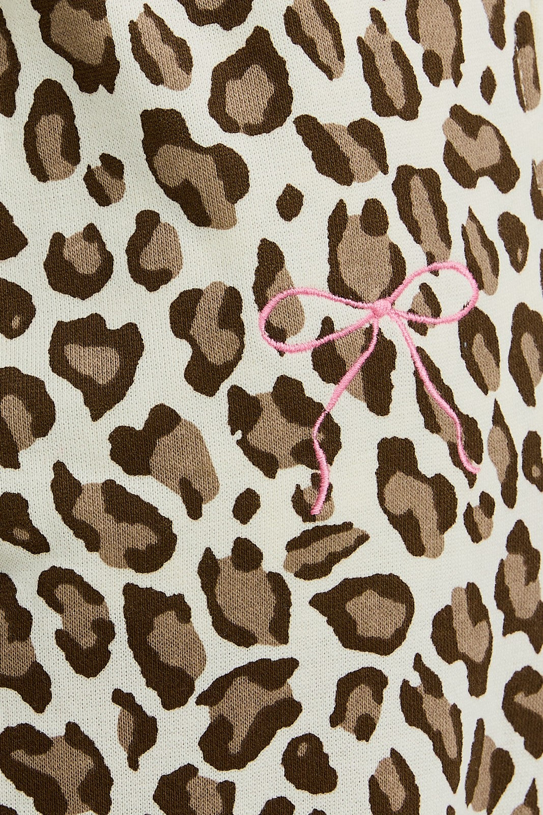 Leopard print fabric with a pink bow on a beige background