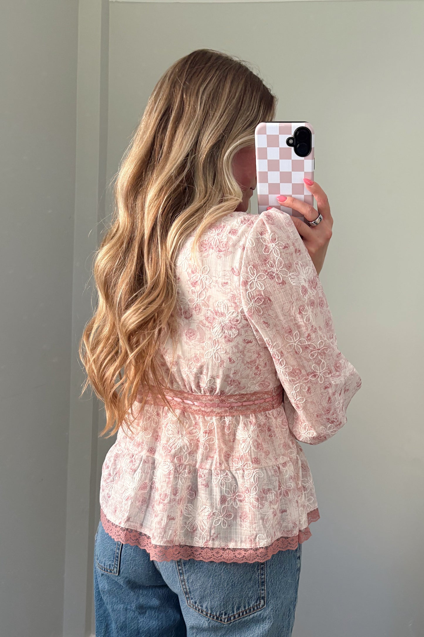 person wearing a babydoll pink blouse in a mirror photo