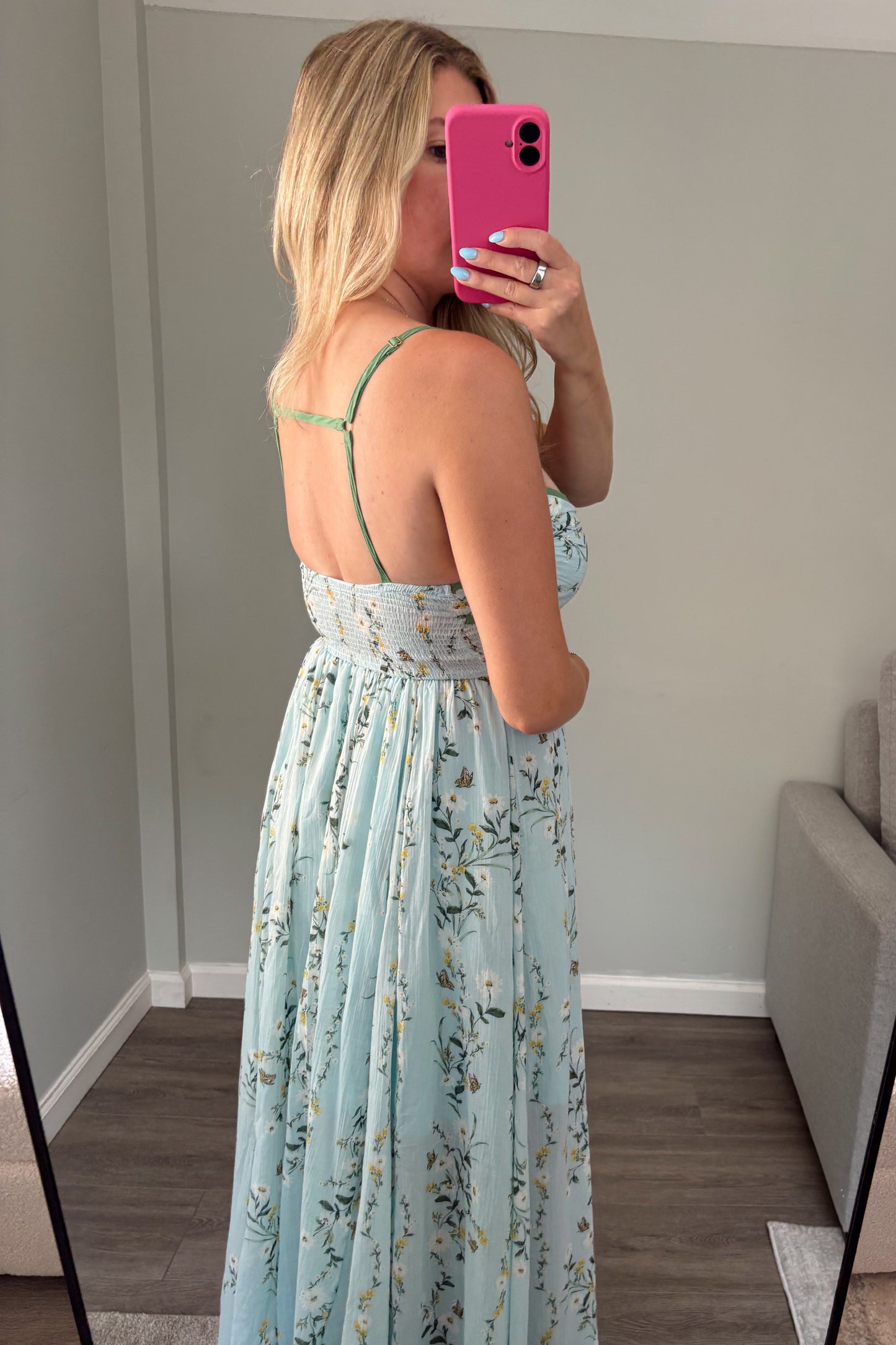 Woman taking a mirror selfie wearing a light blue floral dress.