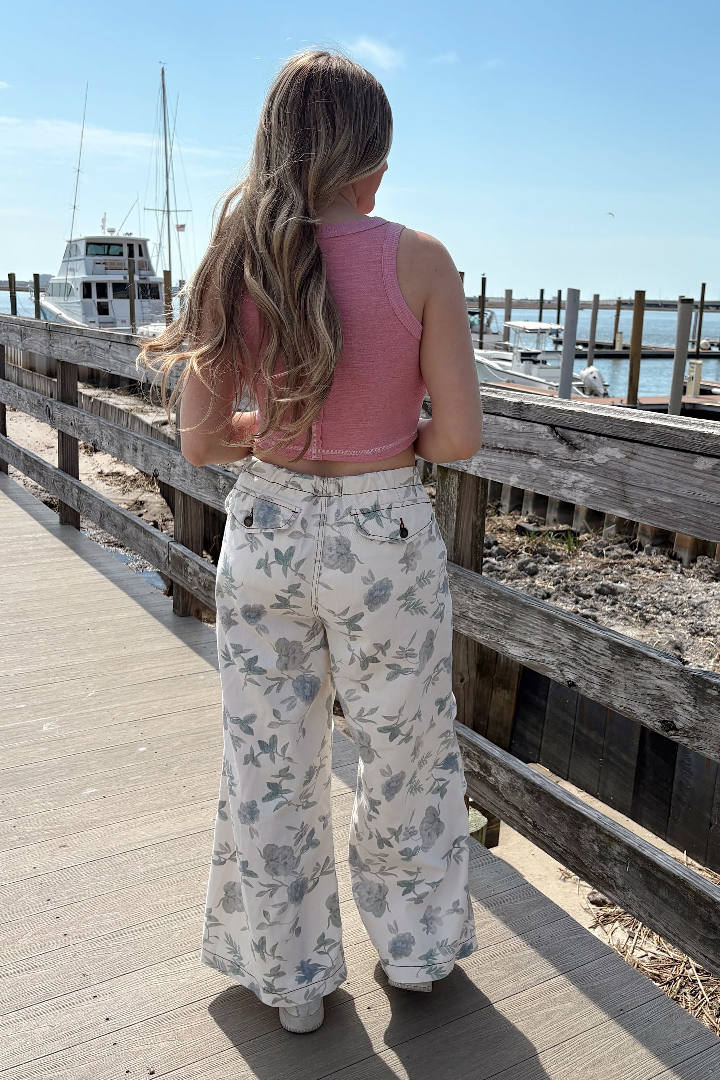 Person standing on a wooden pier with a clear blue sky