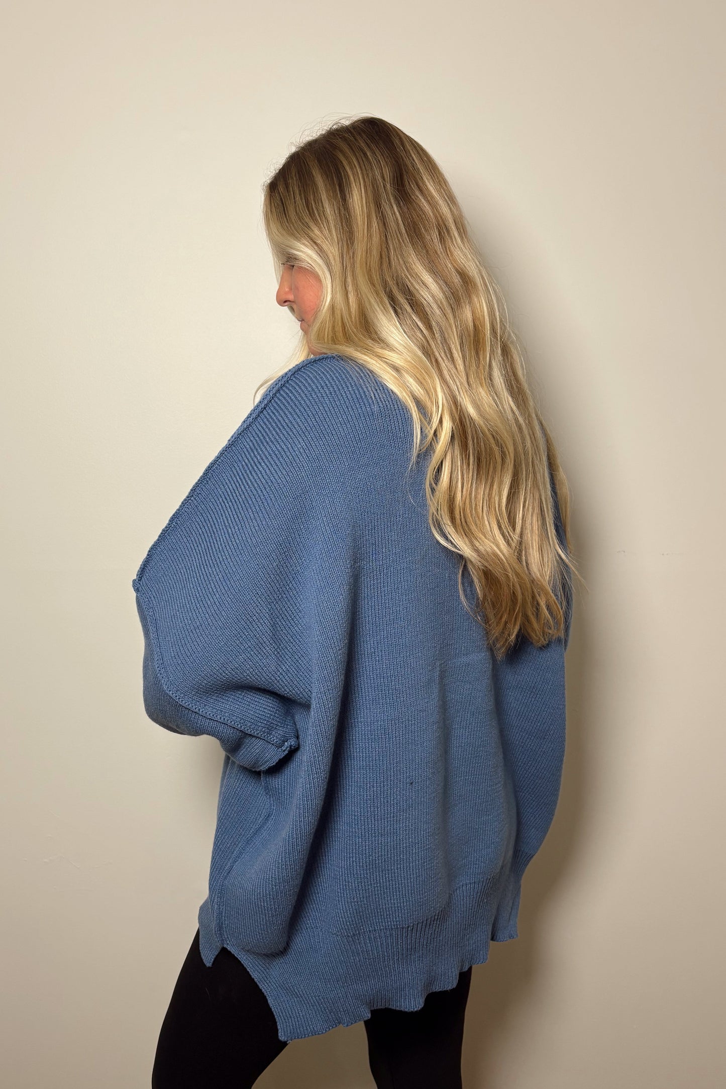 Person wearing a blue sweater against a plain background