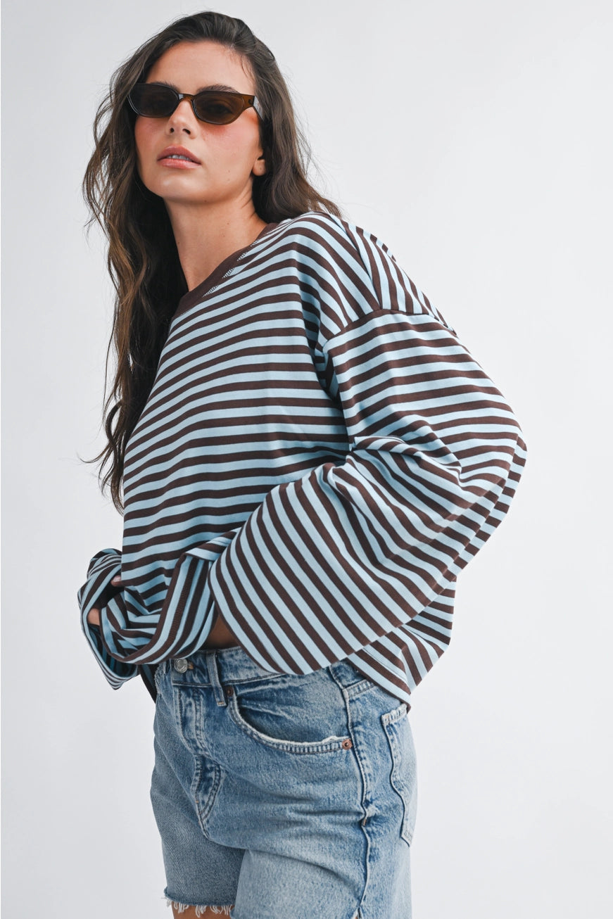 Woman wearing a striped top and sunglasses against a plain background