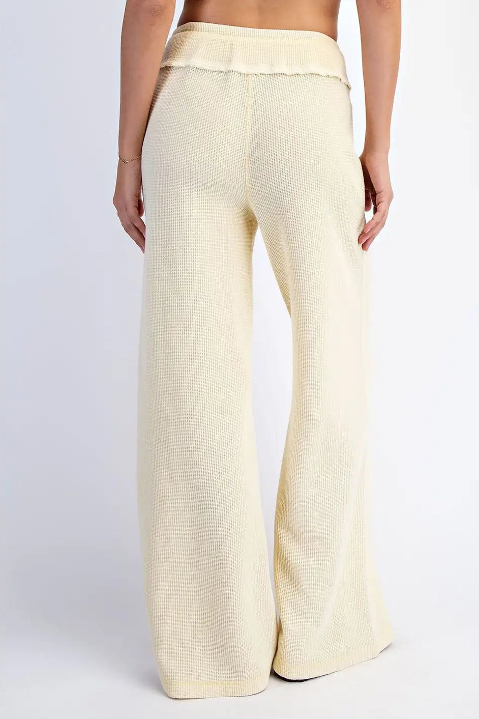Cream-colored wide-leg pants worn by a person on a white background