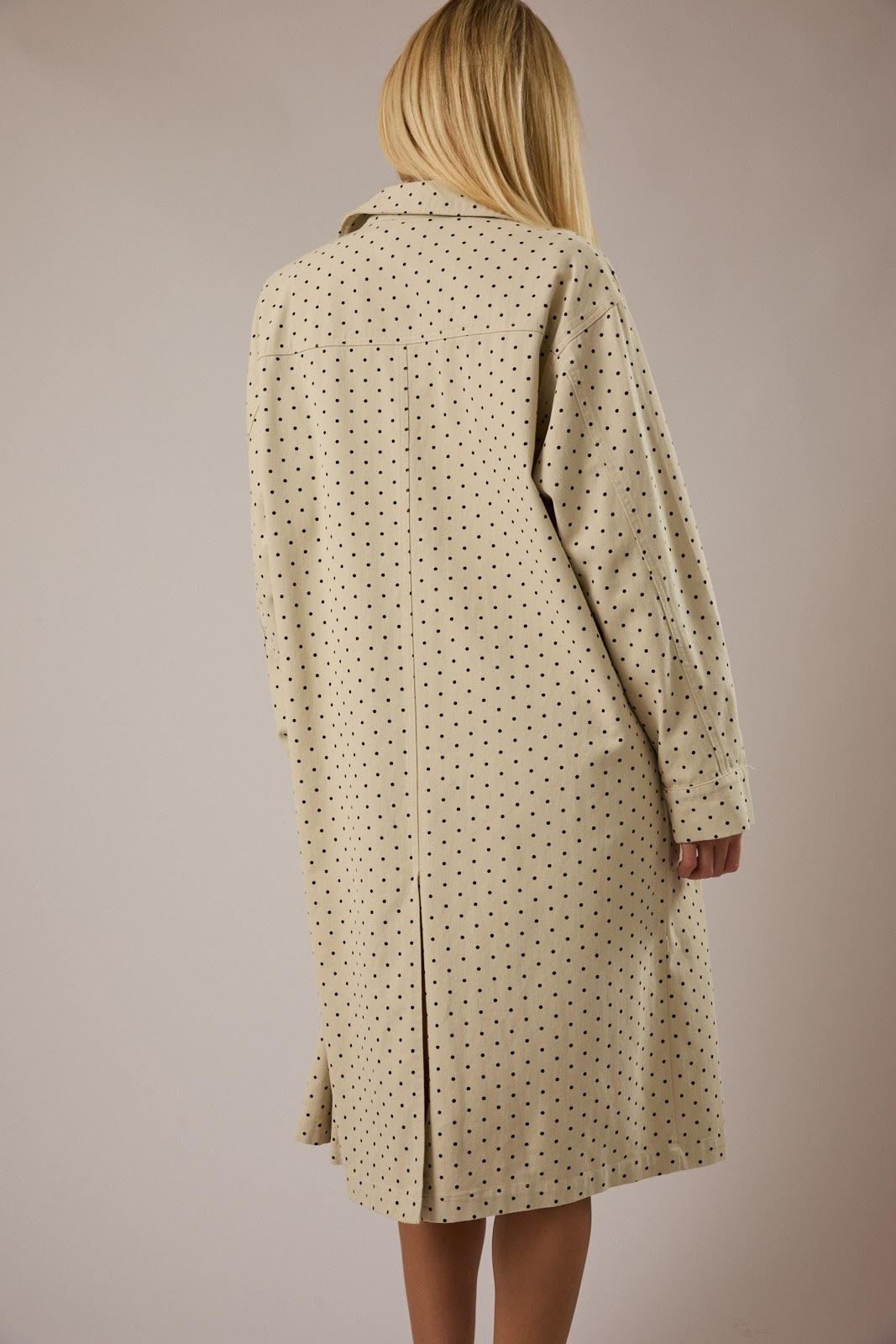 Beige polka dot coat worn by a person on a beige background