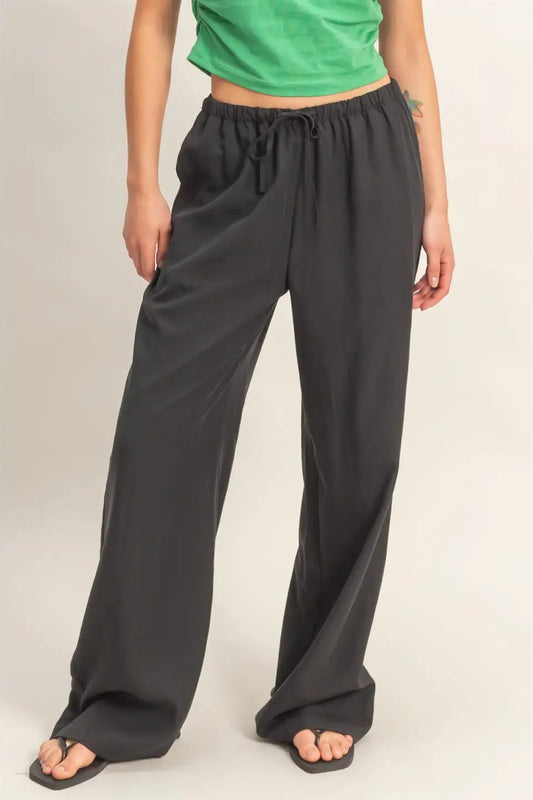 Person wearing black wide-leg pants and a green top on a plain background
