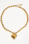 Paris gold-tone heart pendant necklace laid flat on a cream background, showing its beaded chain, clasp, and extension.


