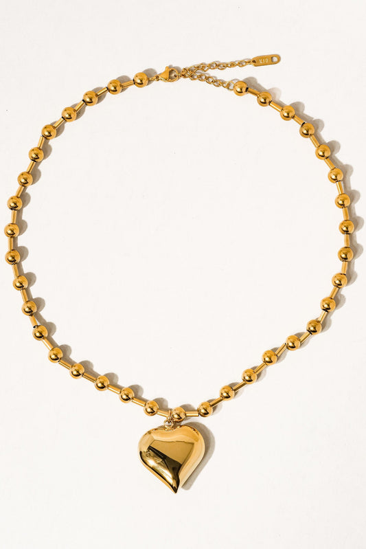 Gold necklace with a heart pendant on a white background