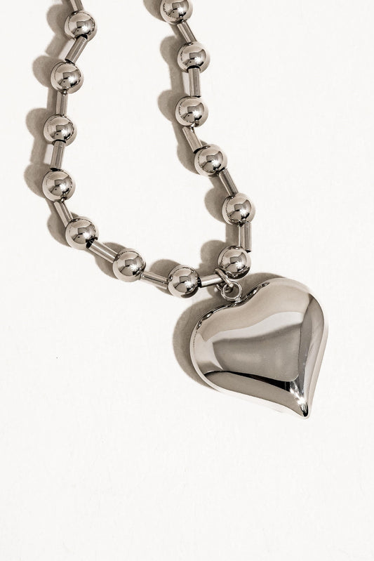 Silver heart-shaped pendant on a chain against a white background