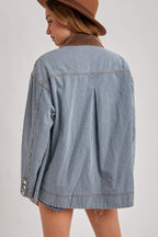 Back view of the Derby striped denim barn jacket showing the brown corduroy collar, center pleat, and contrast stitching.

