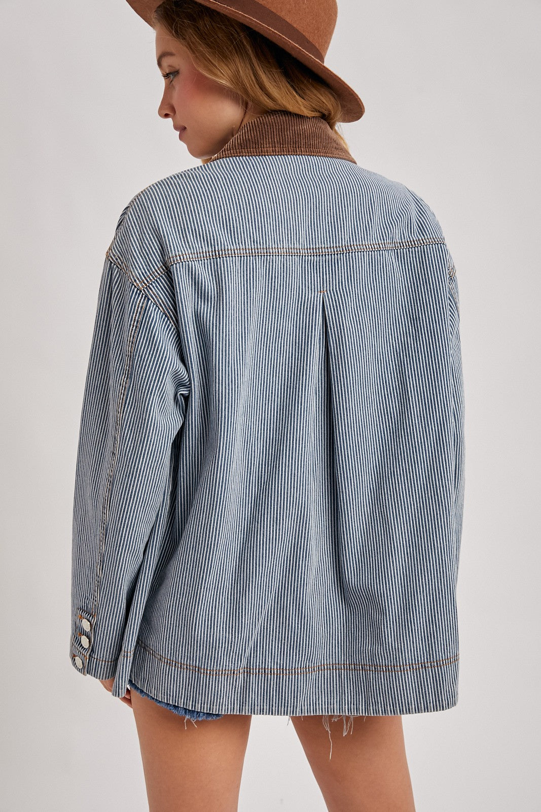Back view of the Derby striped denim barn jacket showing the brown corduroy collar, center pleat, and contrast stitching.

