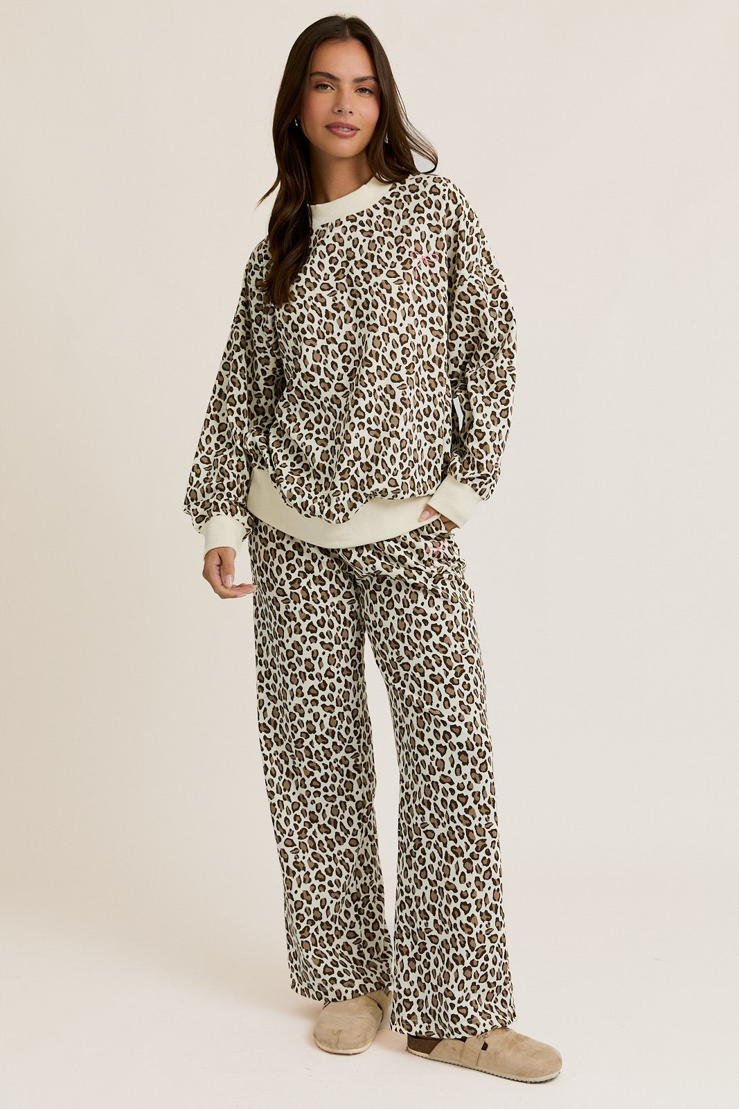 Woman wearing a leopard print pajama set on a beige background