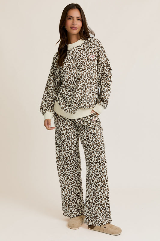 Woman wearing a leopard print pajama set on a beige background
