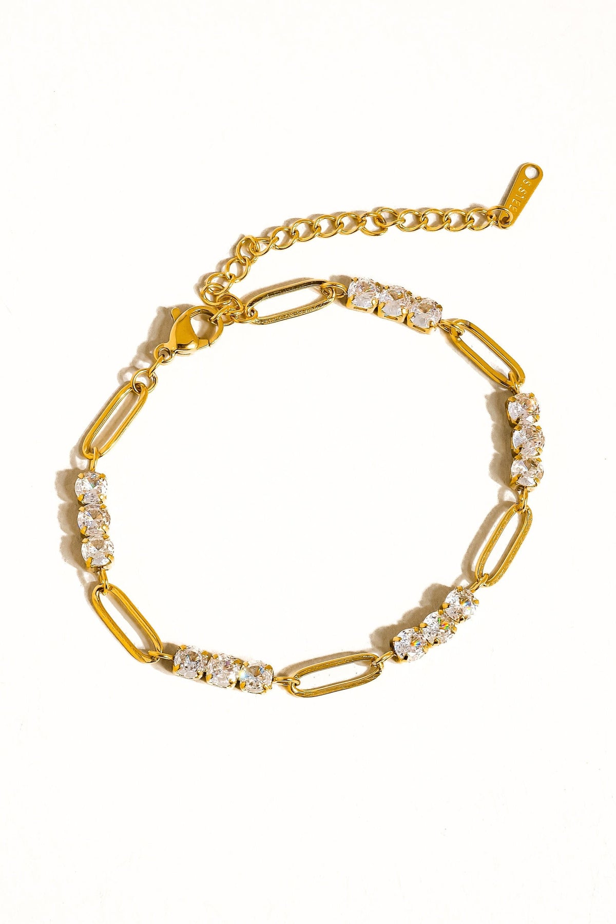 Basil rhinestone chain-link bracelet laid flat on a white background, showing the gold-tone links, clear stones, lobster clasp, and extension chain.

