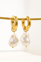 Oceana faux pearl hoop earrings hanging from a gold-tone cord against a cream background, showing both pearl drops.

