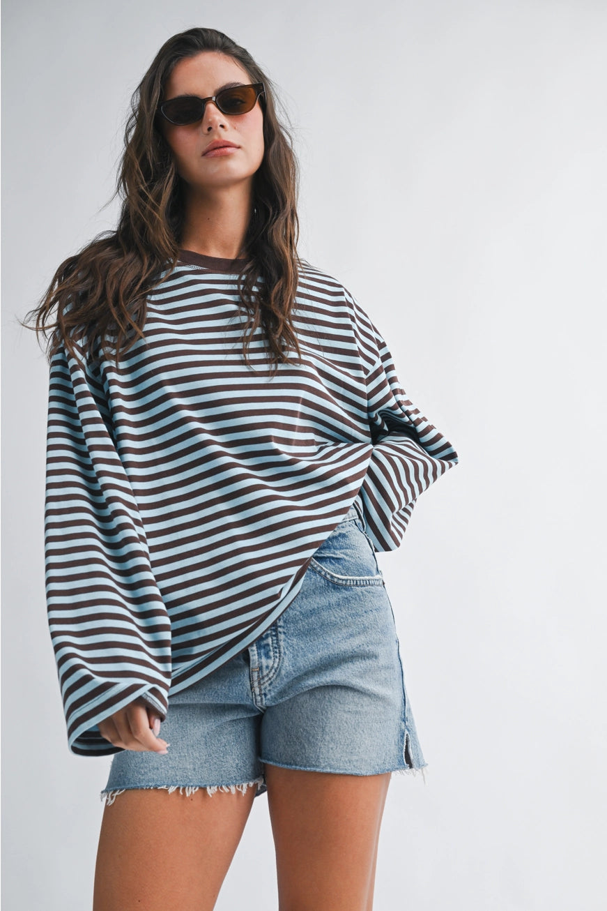 Woman wearing a striped top and denim shorts against a plain background