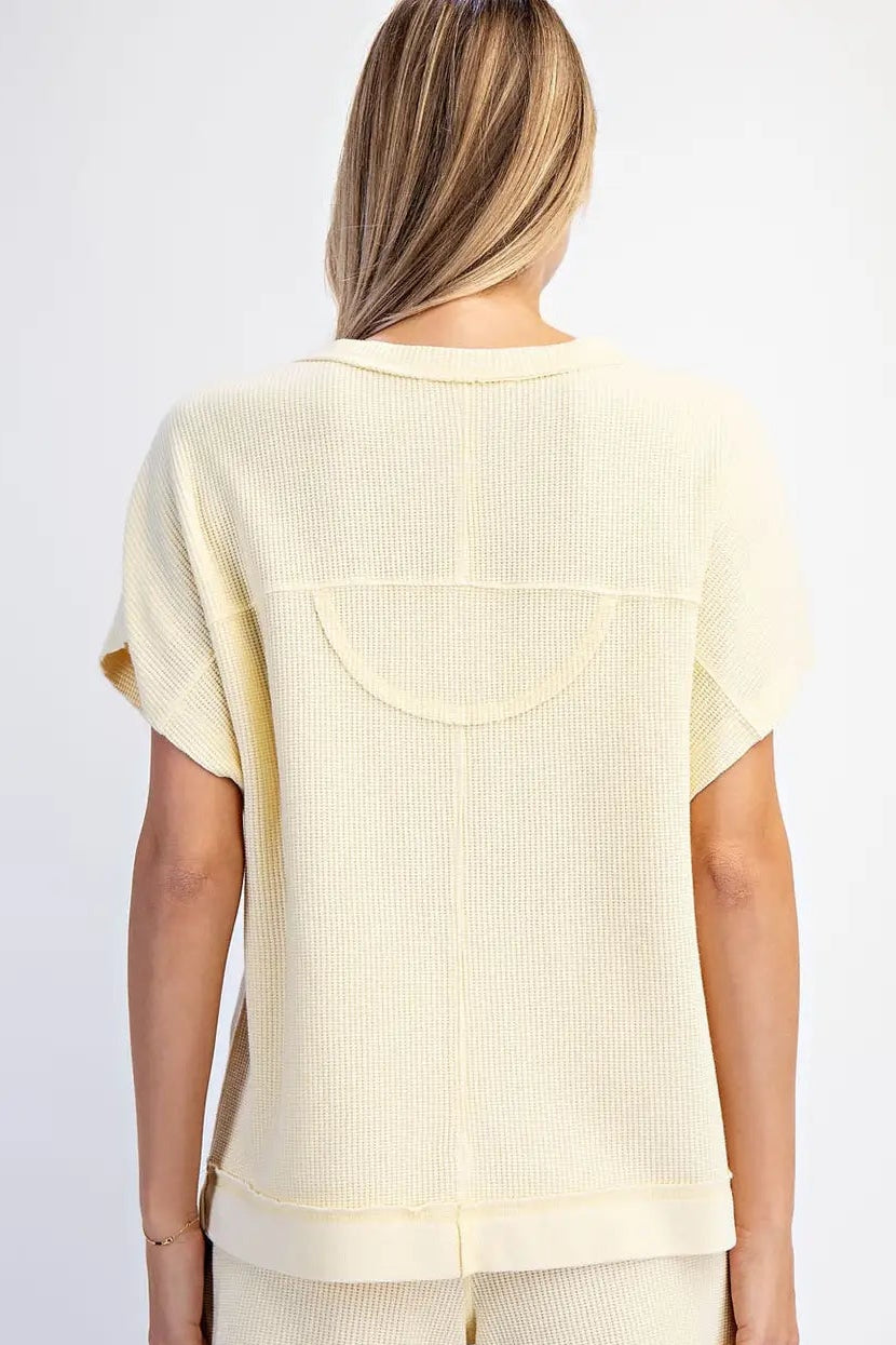Woman wearing a light yellow ribbed top and shorts set on a white background