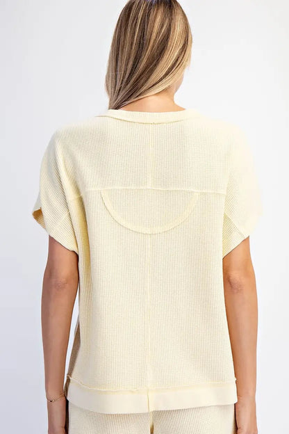 Woman wearing a light yellow ribbed top and shorts set on a white background