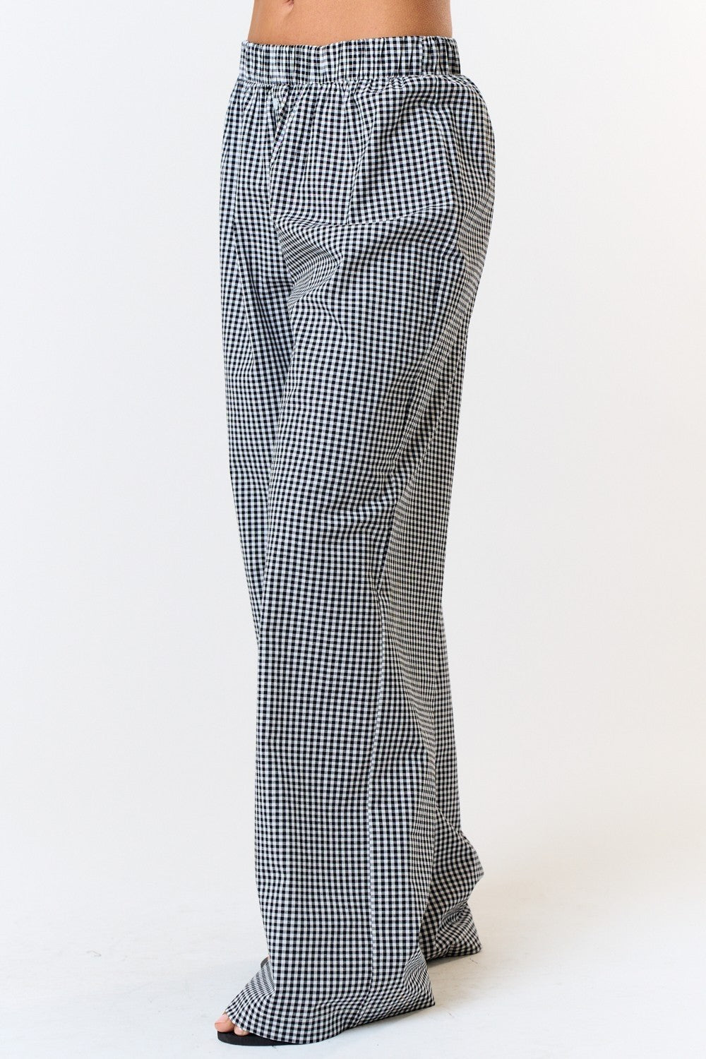 Side view of gingham boxer pants showing the elastic waistband and loose, wide-leg silhouette against a white background.

