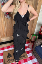 Close-up of the Mia black ruffle maxi dress showing its scoop neckline and rhinestone bows across the tiered skirt.

