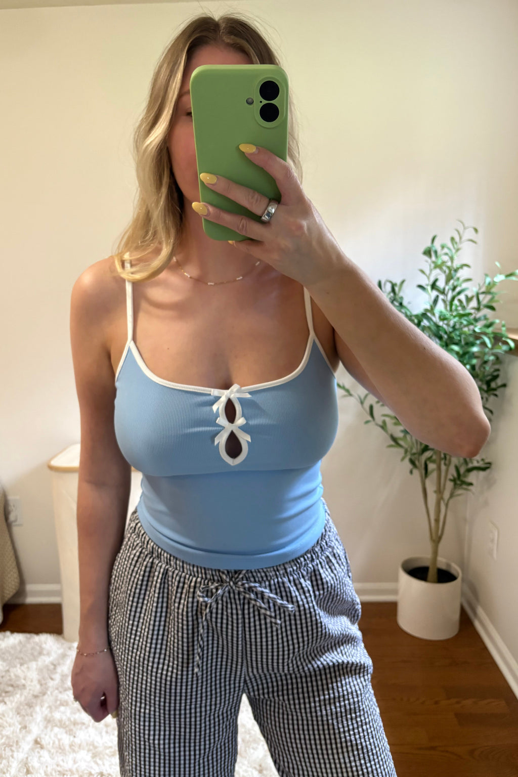 Front view of the Elsie fitted blue tank showing its scoop neckline, white spaghetti straps, and bow cutout details.

