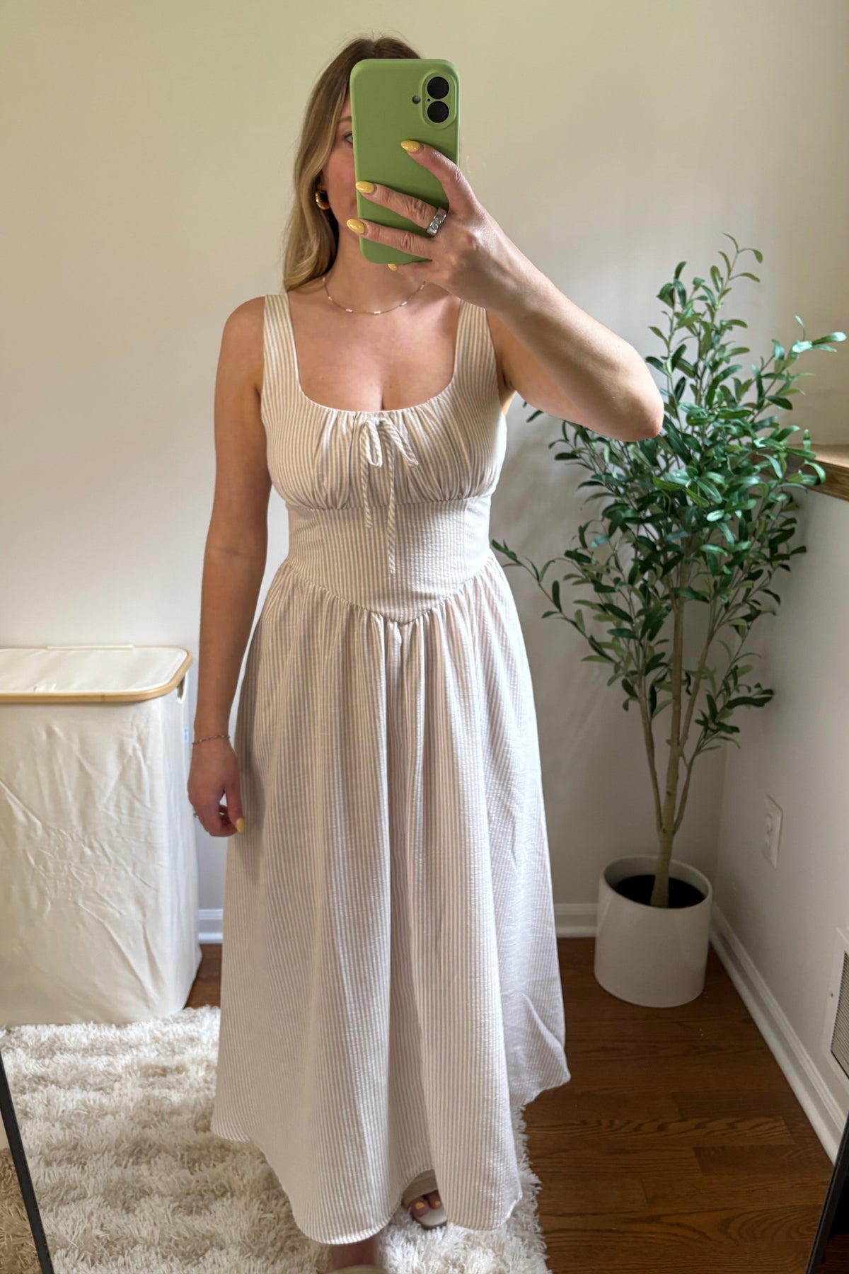 Light-colored striped midi dress with a fitted waist and gathered skirt, shown from the front