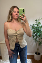Mirror selfie showing the Carli beige tank top with a sweetheart neckline, two front buttons, and a split hem, paired with blue jeans.


