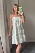 Mirror selfie showing the Meadow Muse floral mini dress with thin straps, a ruffled square neckline, and a loose tiered skirt.

