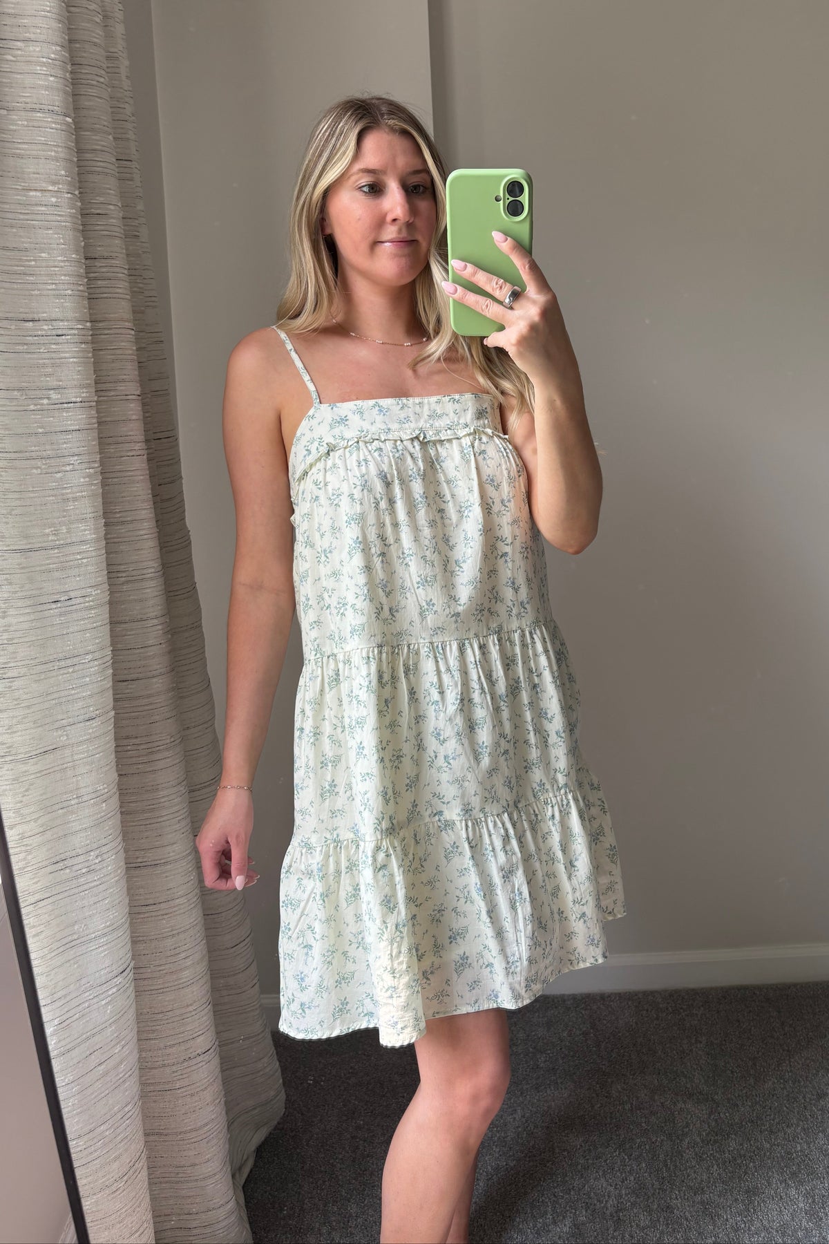 Mirror selfie showing the Meadow Muse floral mini dress with thin straps, a ruffled square neckline, and a loose tiered skirt.

