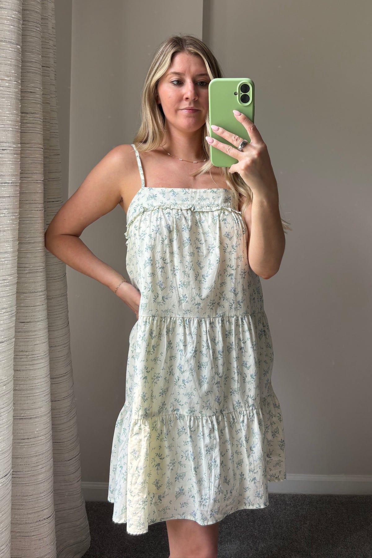 Front mirror view of the Meadow Muse floral mini dress, showing its small blue-green floral print and gathered skirt tiers.

