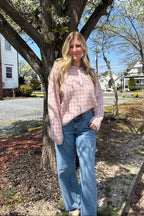 Woman wearing the Rosé pink gingham knit sweater with wide-leg jeans beside a tree