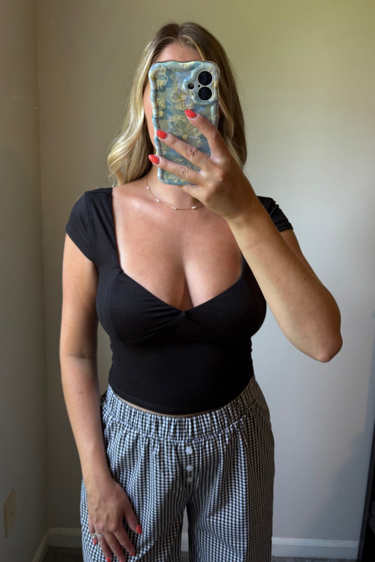 Close front mirror view of the Lark black top showing its sweetheart neckline, fitted shape, and cropped hem above gingham pants.

