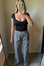 Full-length mirror view of black-and-white gingham boxer pants with wide legs and an elastic waistband, styled with a black crop top.

