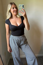 Closer mirror view of gingham boxer pants showing the gathered elastic waist, faux button detail, and relaxed fit.

