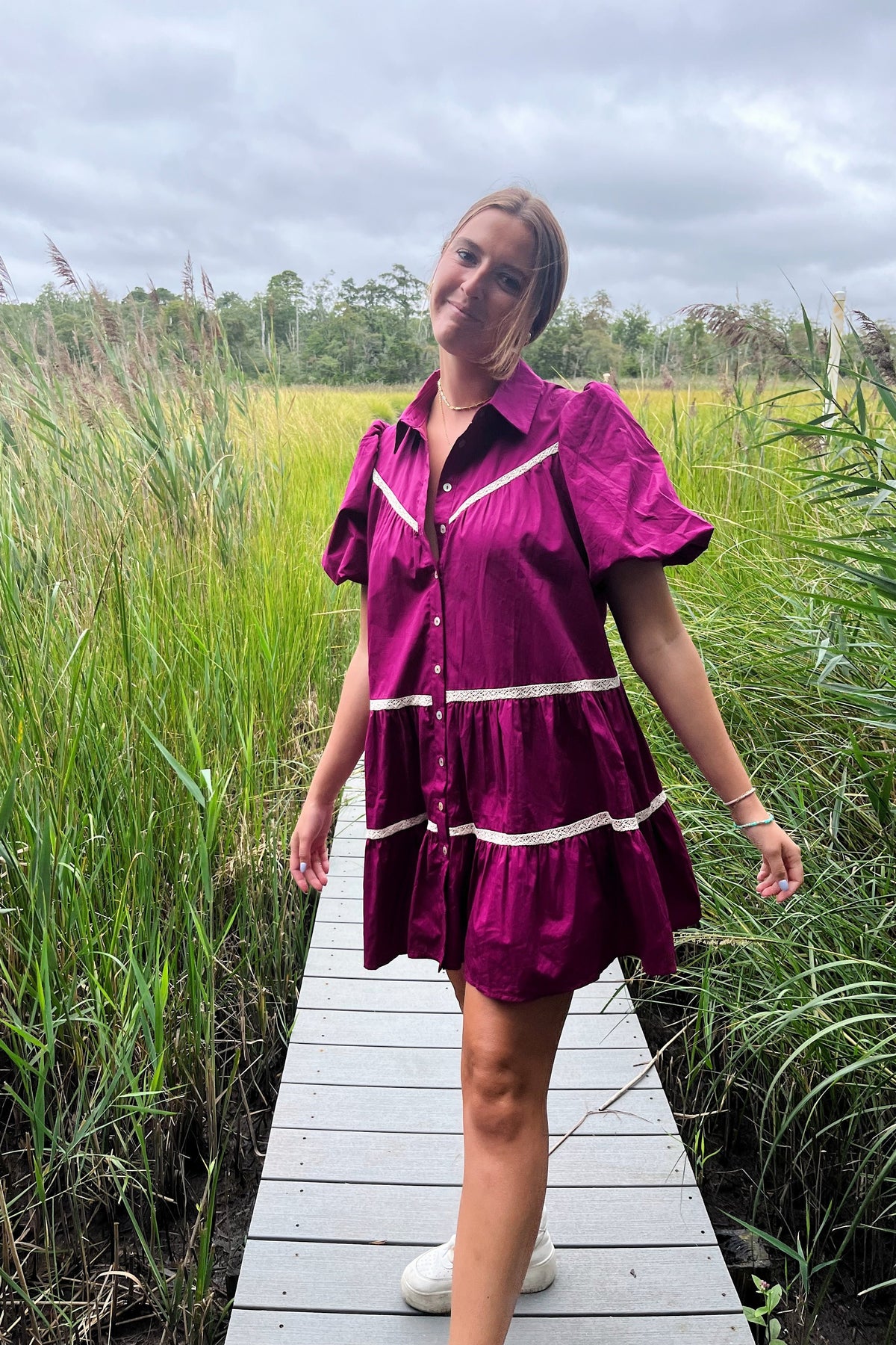 Front view of the Margaret magenta babydoll mini dress showing its collar, puff sleeves, and white crochet trim.

