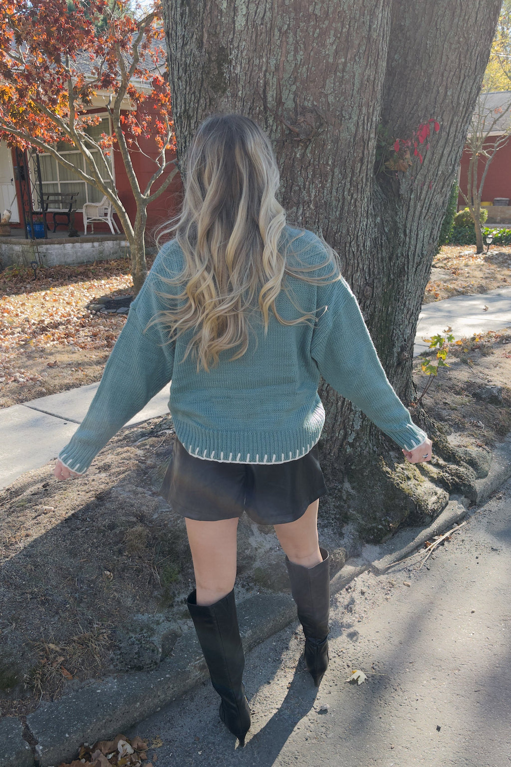 Back view of the Vivian blue knit sweater showing its plain back and cream stitching along the hem and cuffs.

