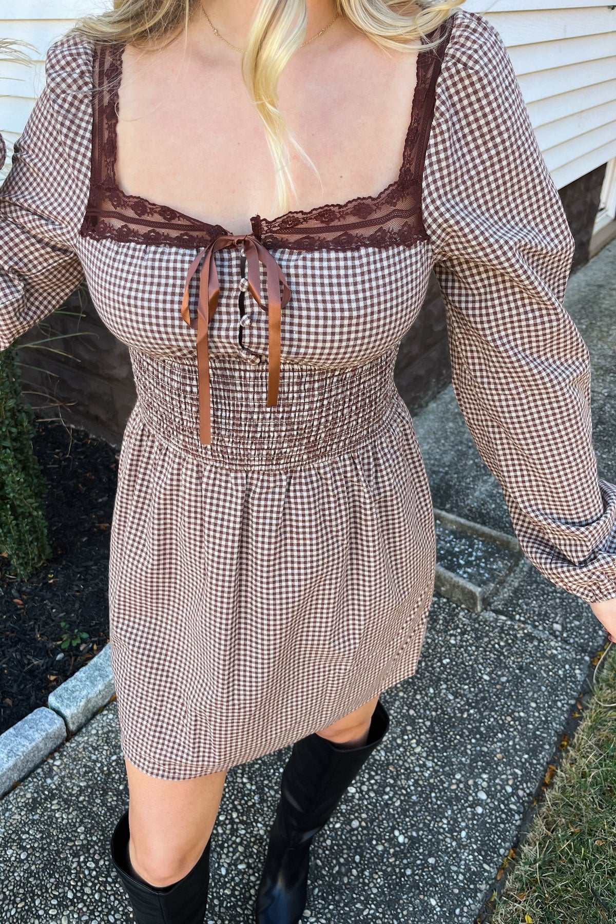 Angled close-up of the Harvest brown gingham dress showing its fitted smocked waist and long puff sleeves.

