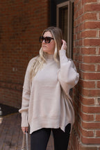 Front view of the Essential sand beige sweater showing its mock neckline, ribbed knit texture, and relaxed fit.

