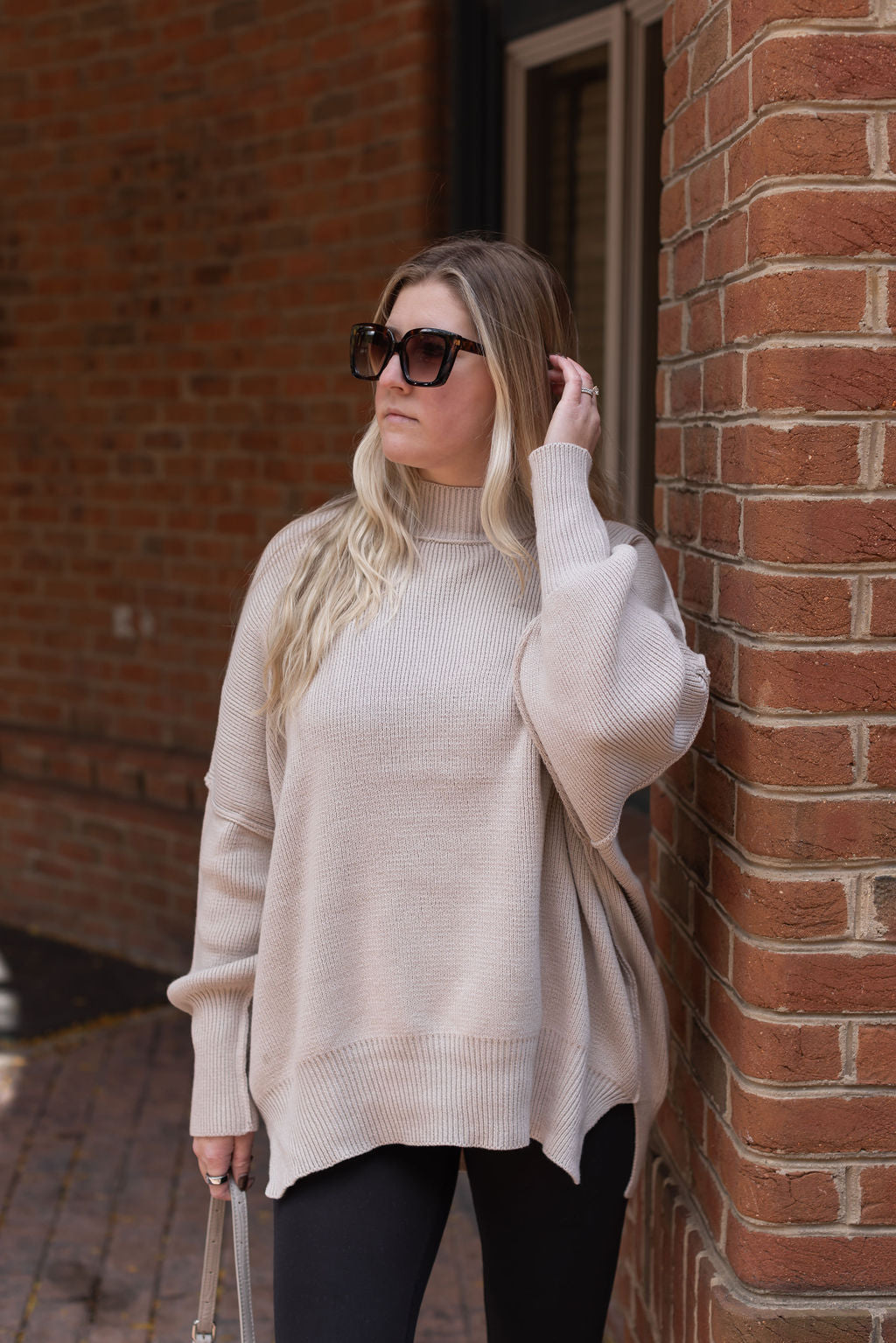 Front view of the Essential sand beige sweater showing its mock neckline, ribbed knit texture, and relaxed fit.

