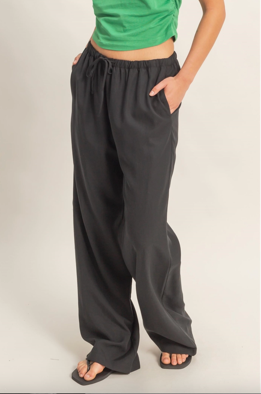 Person wearing black wide-leg pants and a green top on a plain background