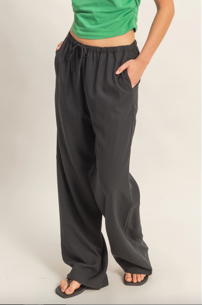Person wearing black wide-leg pants and a green top on a plain background