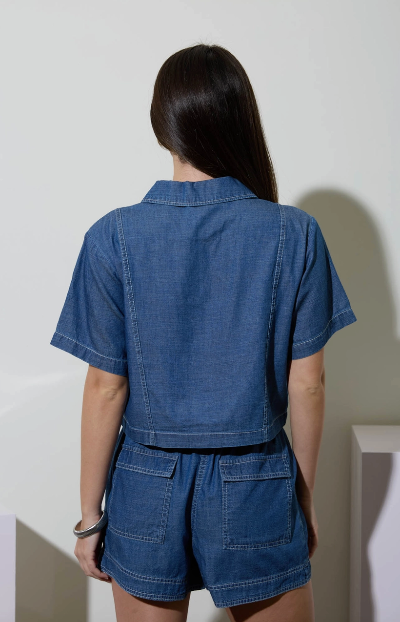 Person wearing a blue denim romper against a plain background