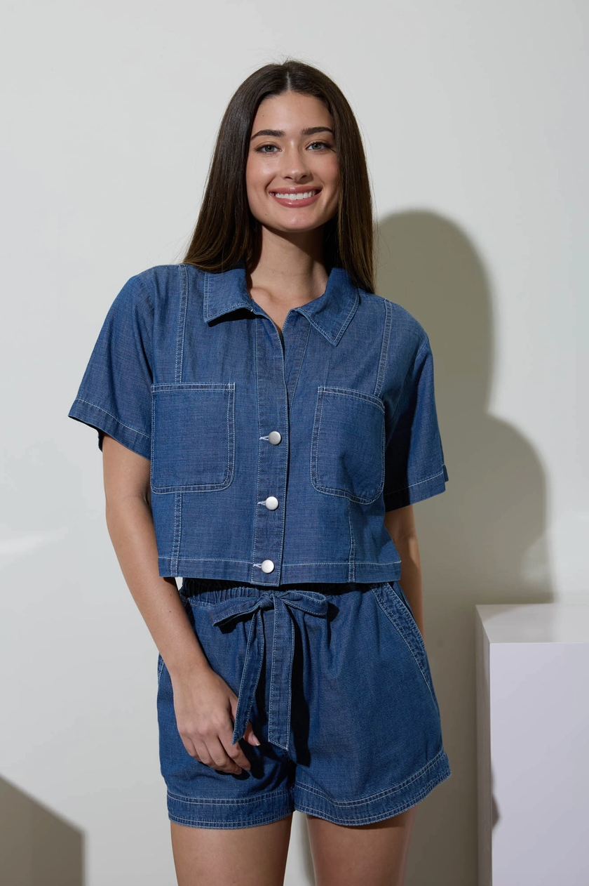 Woman wearing a blue denim outfit against a white background