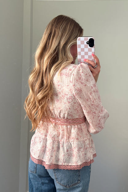 person wearing a babydoll pink blouse in a mirror photo