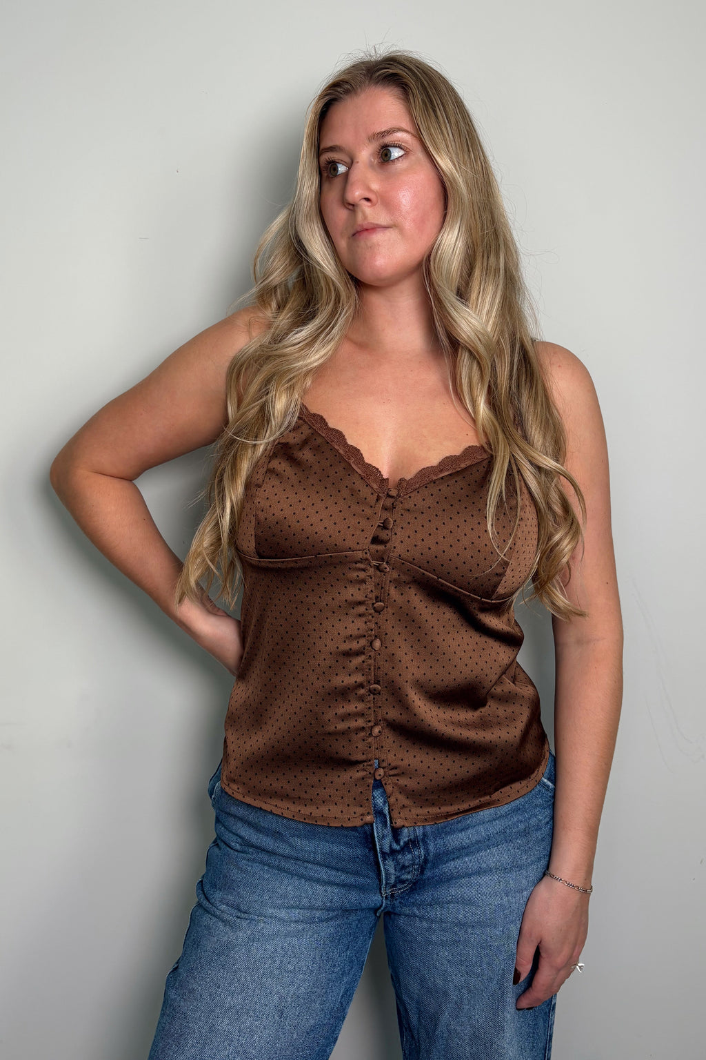 Model looking to the side in the brown polka dot Delancey cami with corset seam details, paired with blue jeans
