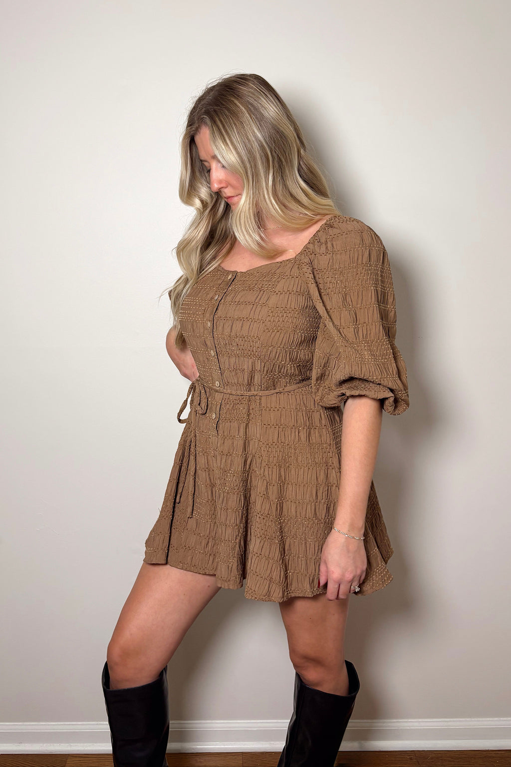 Angled view of the Brielle brown romper showing its gathered bubble sleeve, button front, and braided waist belt.

