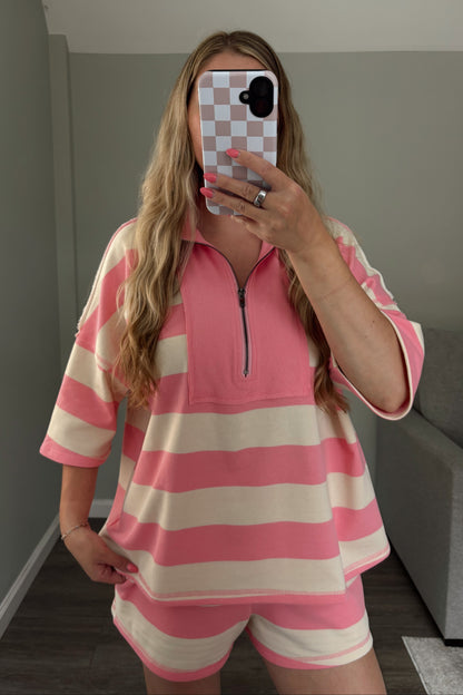Person wearing a pink and white striped outfit taking a mirror selfie.