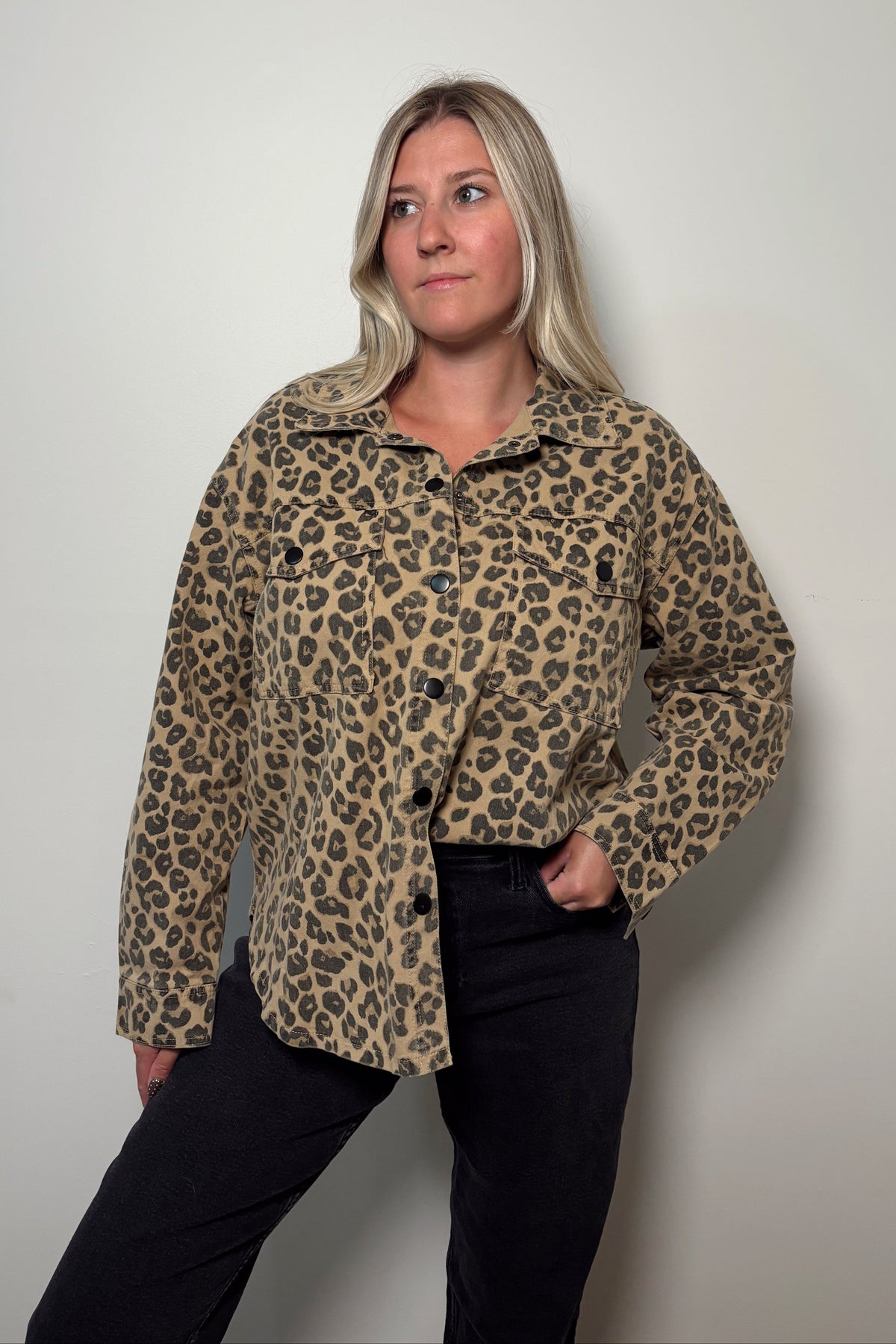 Wild Muse leopard print shacket buttoned at the front and partially tucked into black jeans, showing the dark buttons and chest pockets.

