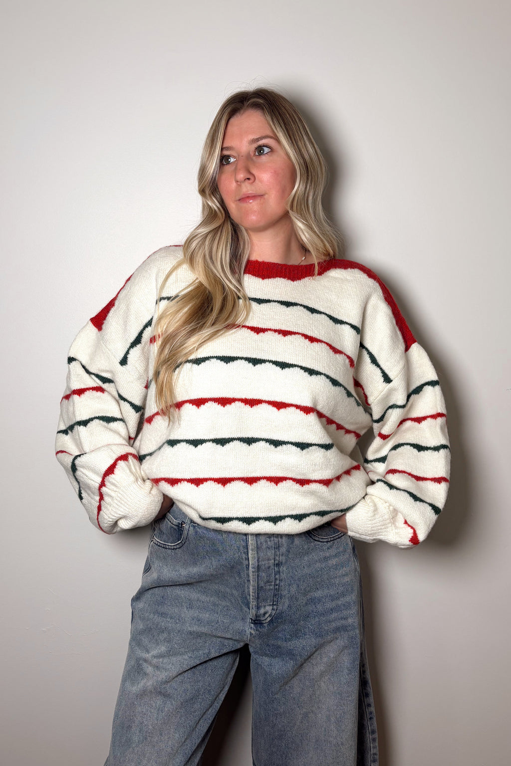 Person wearing a striped sweater and jeans against a plain background
